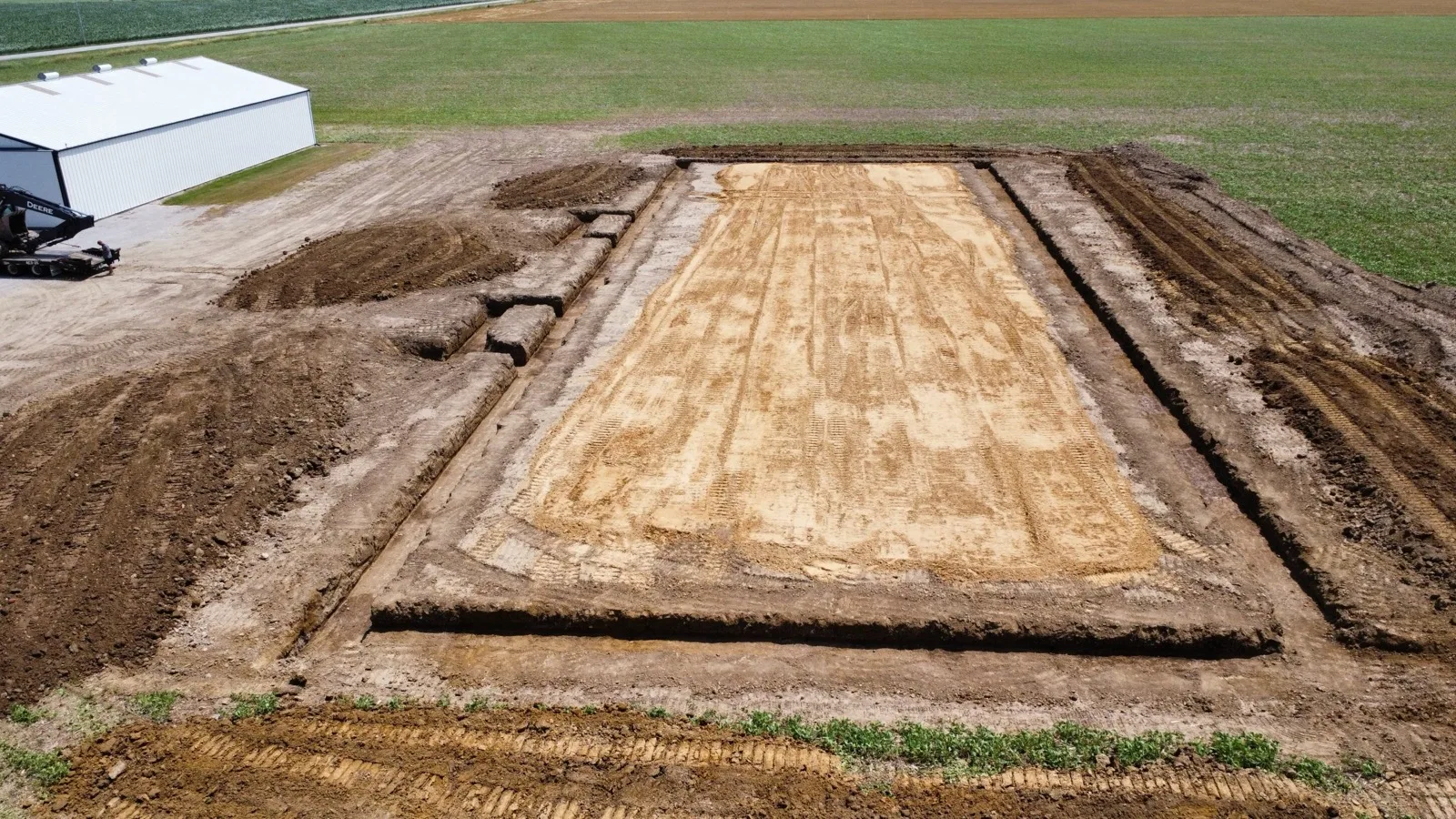 Aerial view of a graded rectangular building pad cut into a field