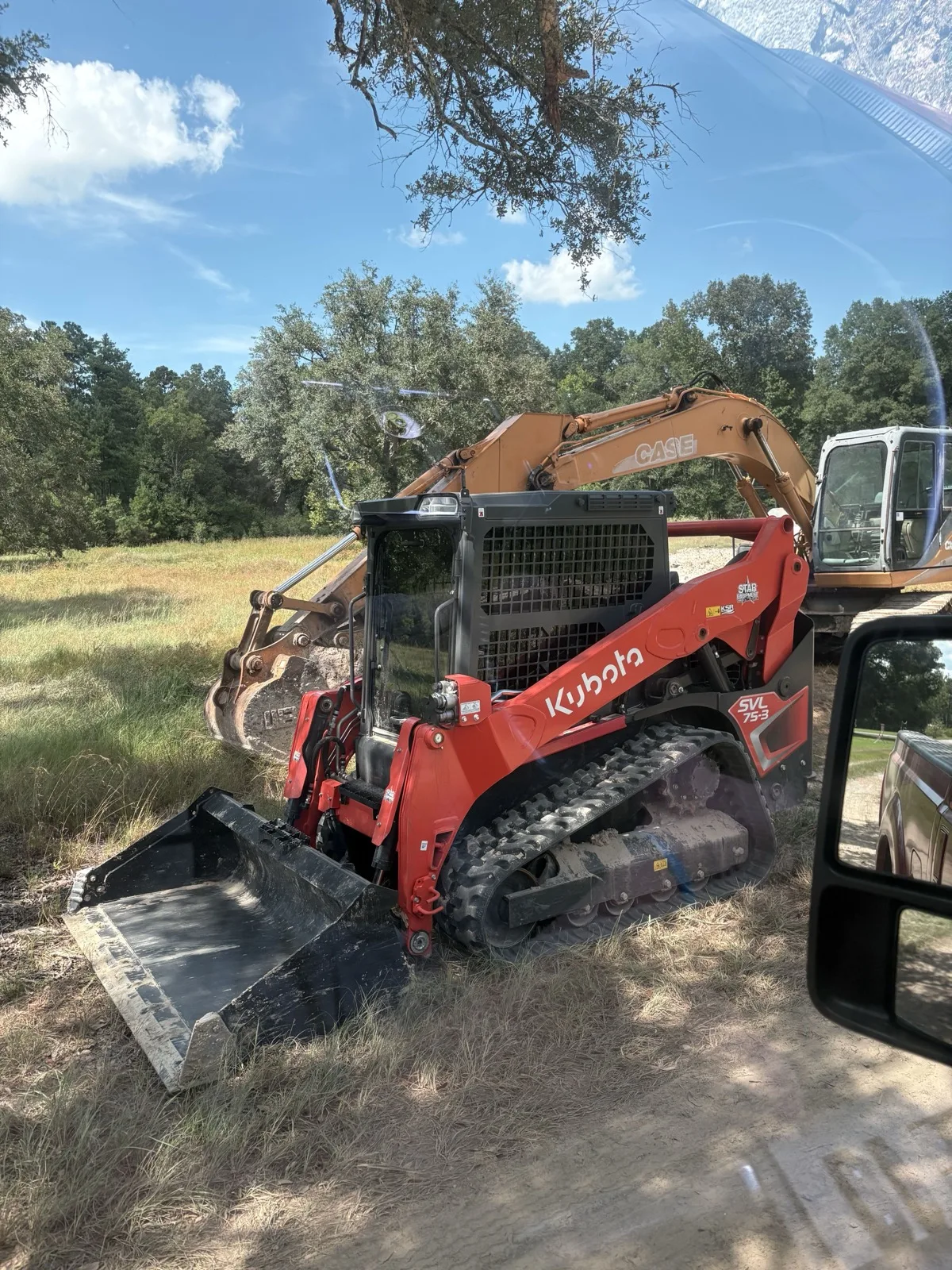 Kubota SVL75-3 tracked skid steer parked in front of a Case excavator on a job site near Hammond, LA